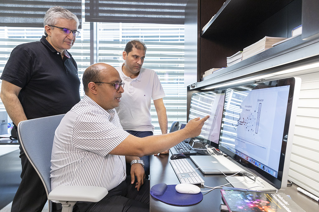 Osama Amin discusses the system architecture with advisors Mohamed-Slim Alouini and Basem Shihada (back).