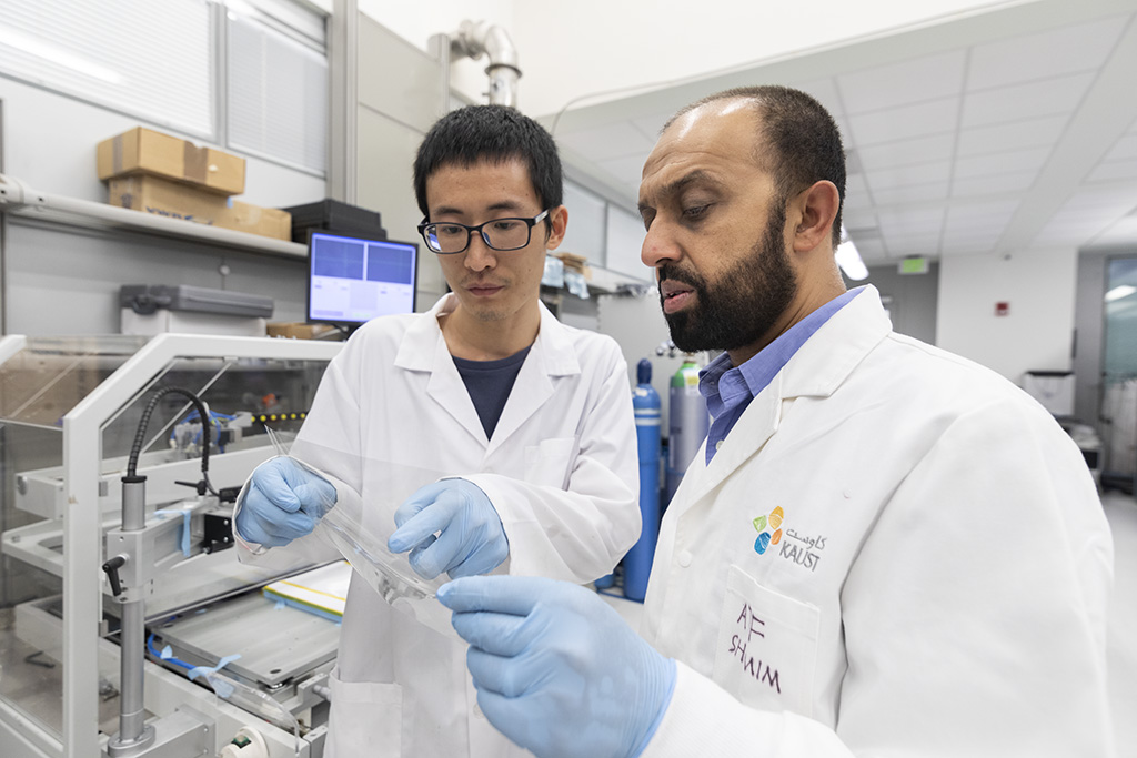 Weiwei Li (left) and Atif Shamim discuss their transparent, conducting sheet printed with their electromagnetic-wave-blocking nanowire-polymer ink.