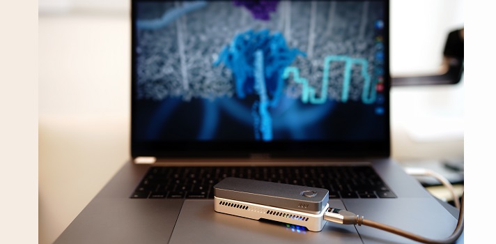 The sequencing setup for the study: an Oxford Nanopore sequencer and a laptop computer. The screen in background shows the DNA strand fed through the sequencer.